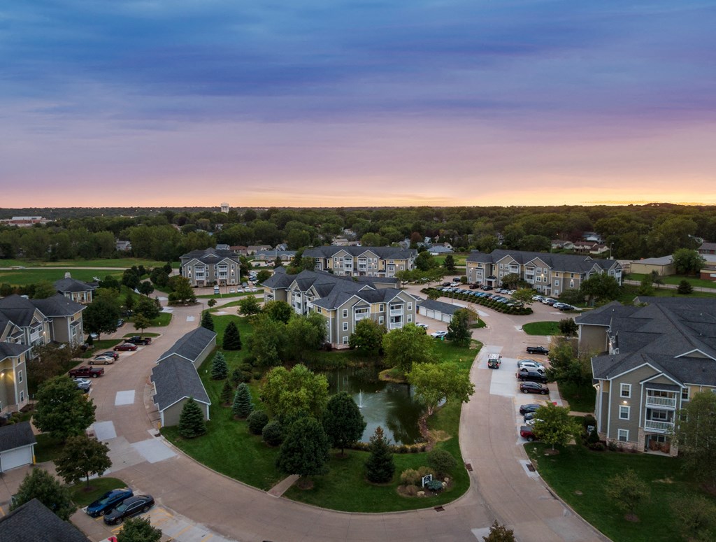 an aerial view of a neighborhood with houses and a pond at sunset