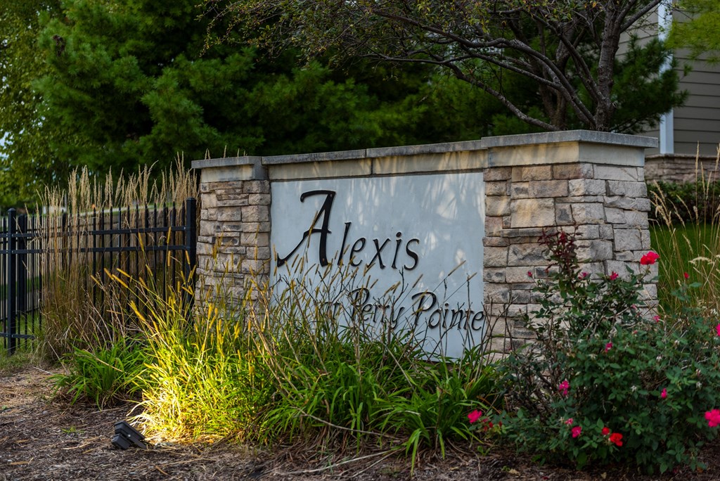sign in front of a stone wall with flowers