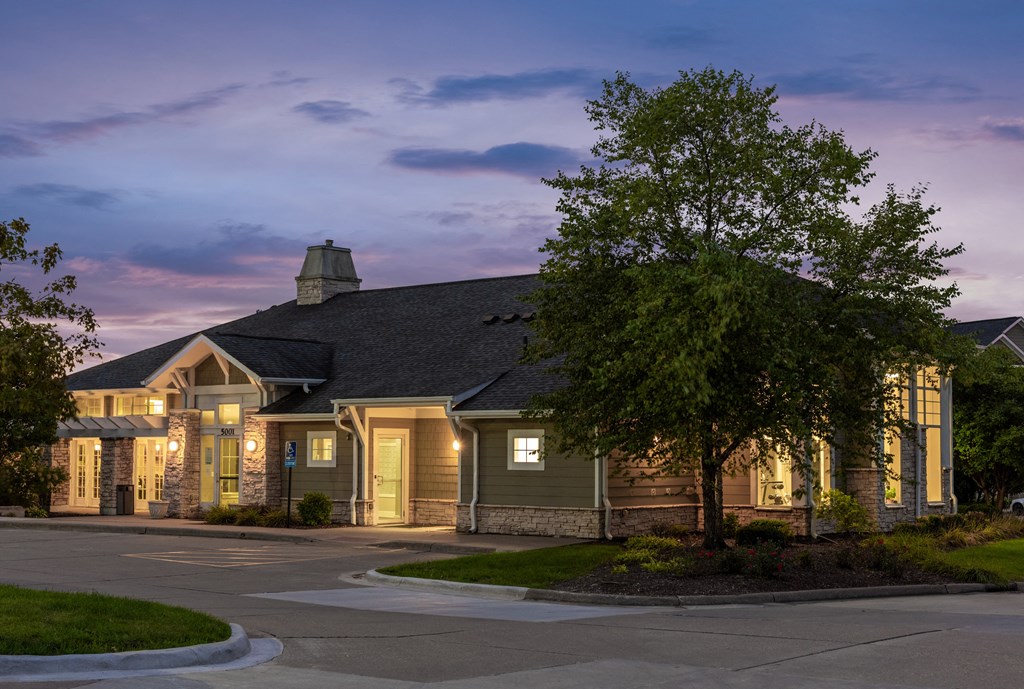 a home at dusk with lights on in the windows and a tree