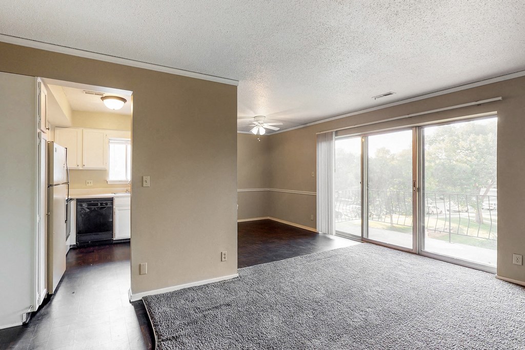 an empty living room and kitchen with sliding glass doors