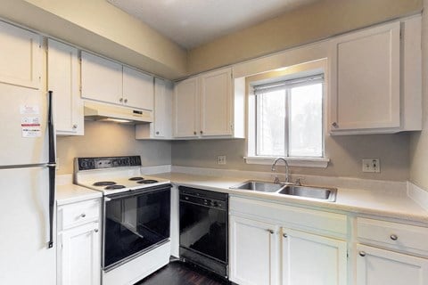 a kitchen with white cabinets and black appliances and a window