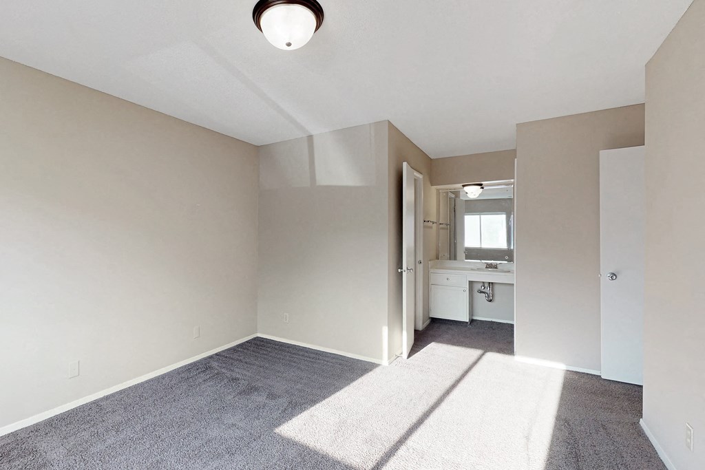 an empty living room with a sink and a door to a bathroom