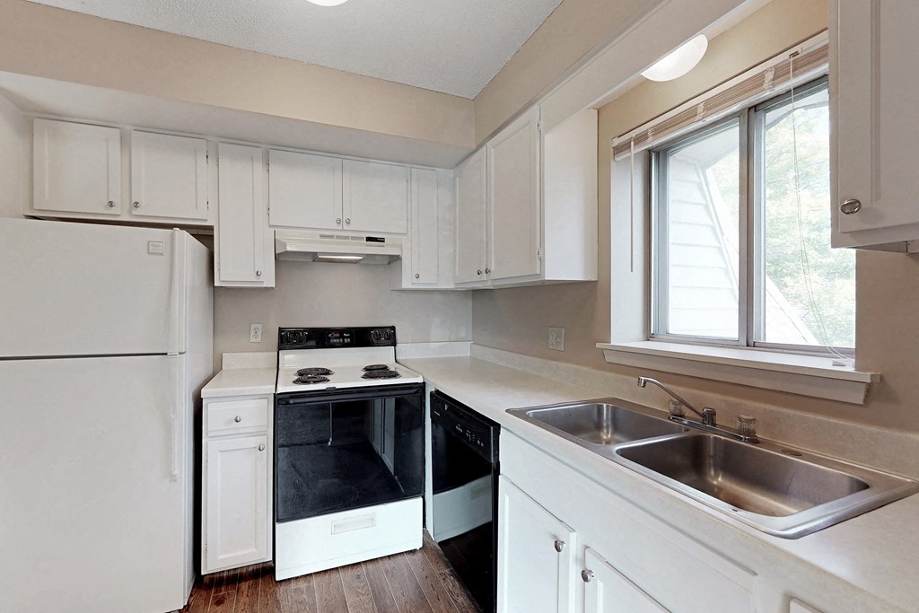 an empty kitchen with white cabinets and white appliances and a sink