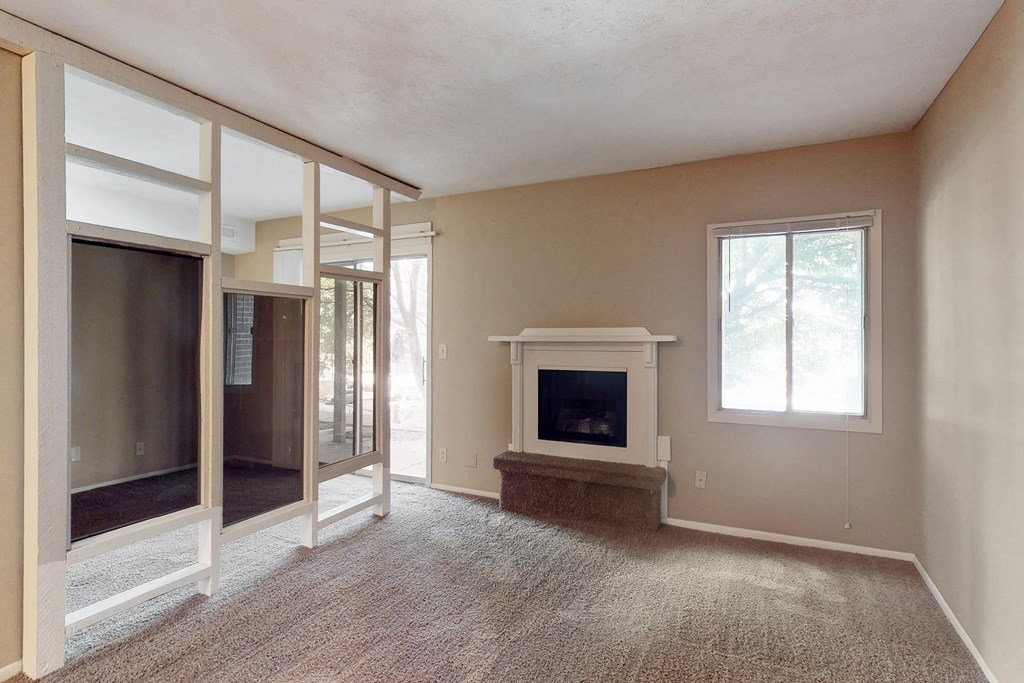 an empty living room with a fireplace and mirrored closets