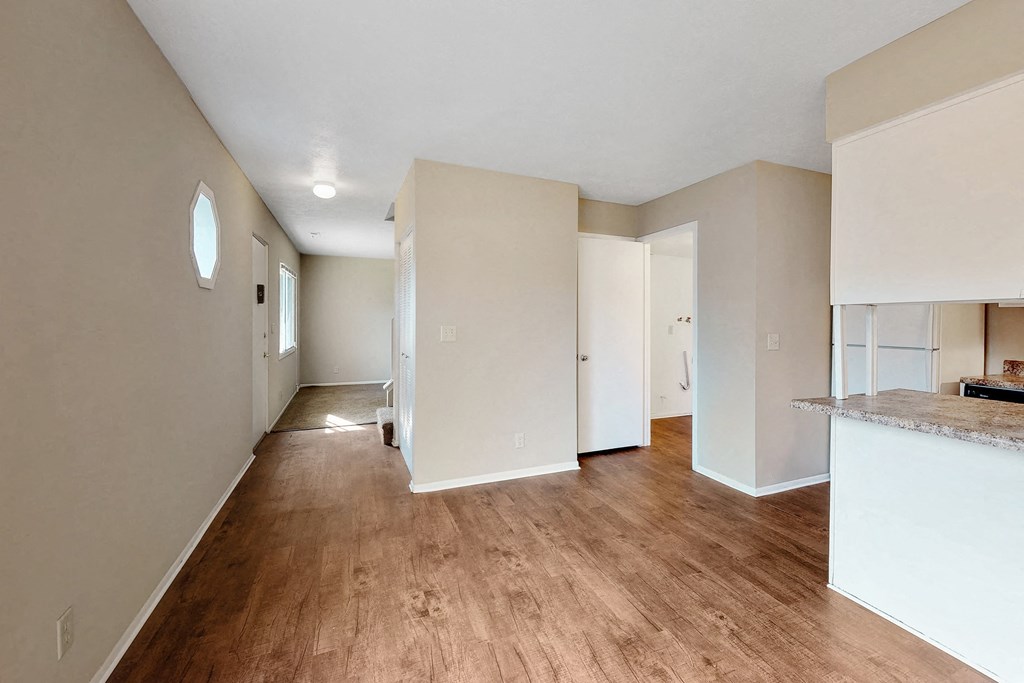 a renovated living room and kitchen with hardwood floors and white walls