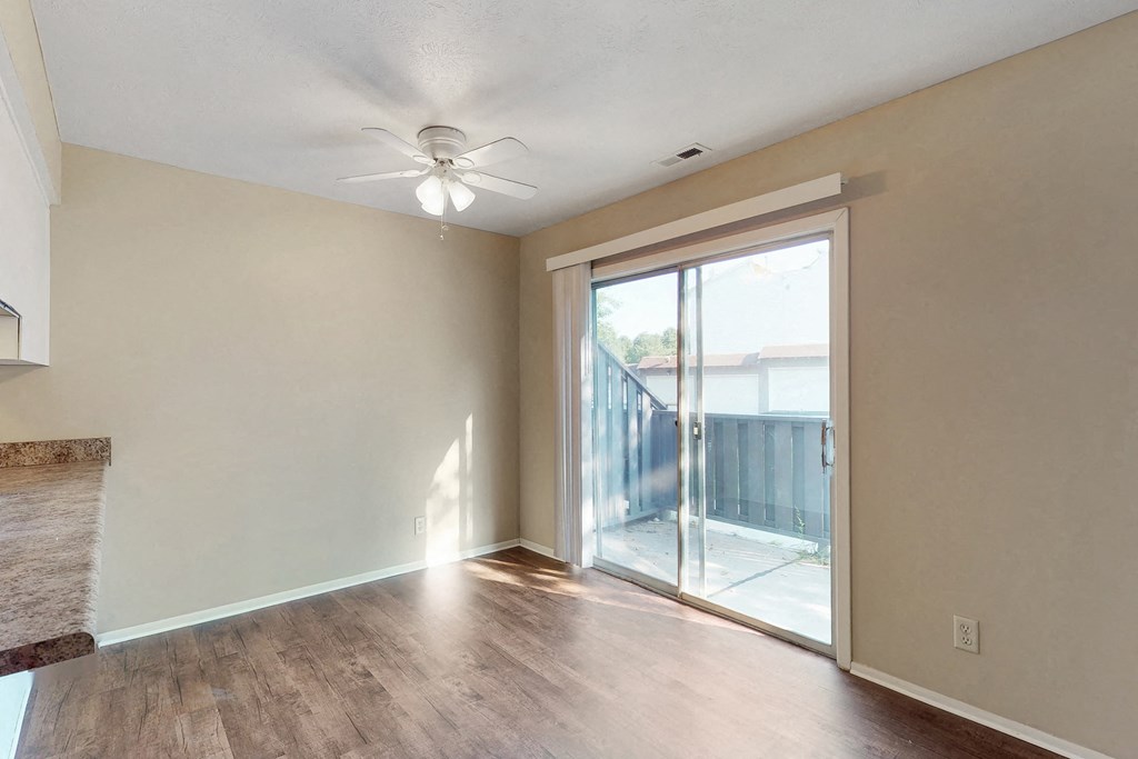 an empty living room with a sliding glass door to a balcony