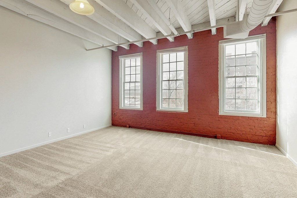 an empty room with a brick wall and three windows