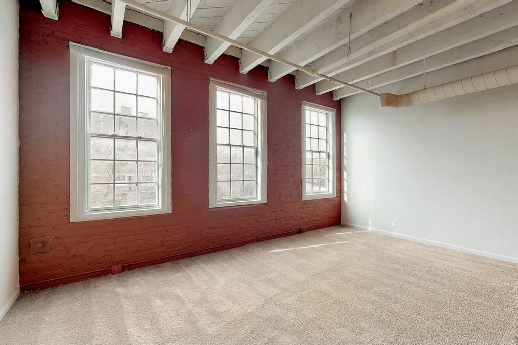 an empty room with three windows and a carpeted floor