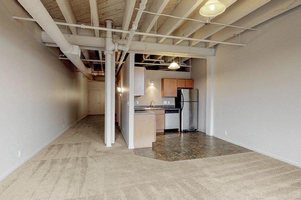 a renovated basement with a kitchen and exposed ceilings