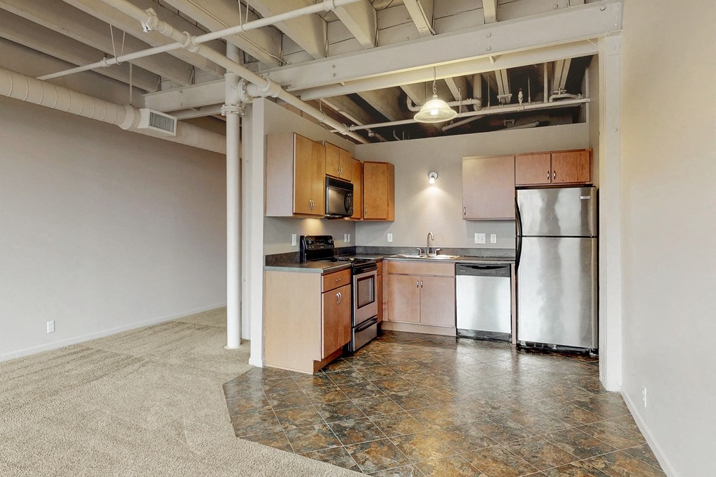 an empty kitchen with stainless steel appliances and wood cabinets