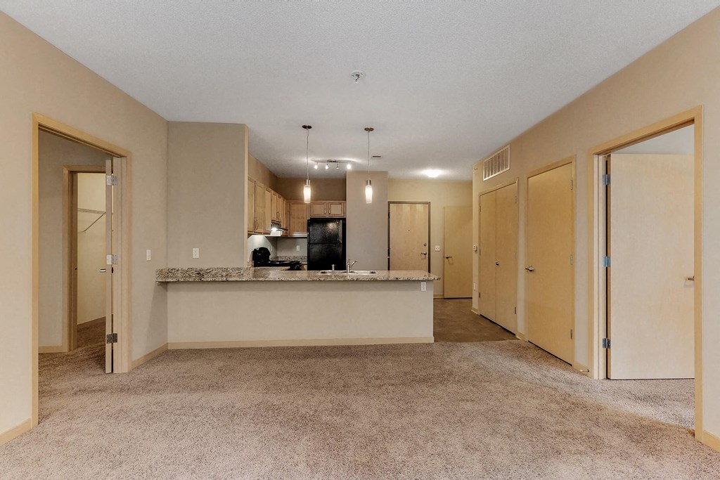 an empty living room and kitchen with a counter in the middle