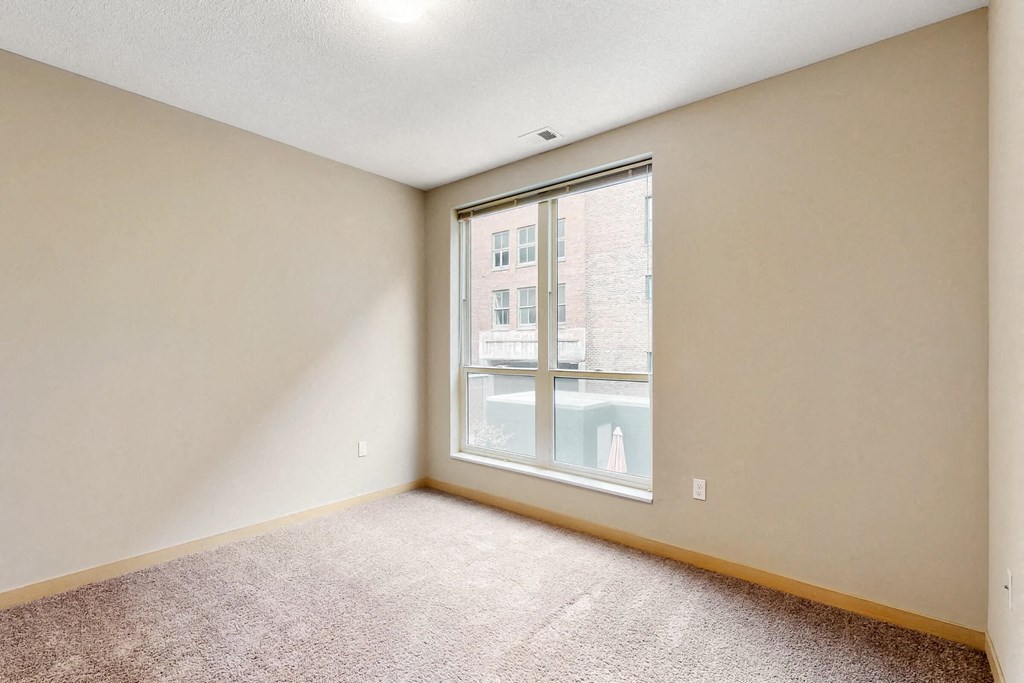 a bedroom with a large window and carpeted floors