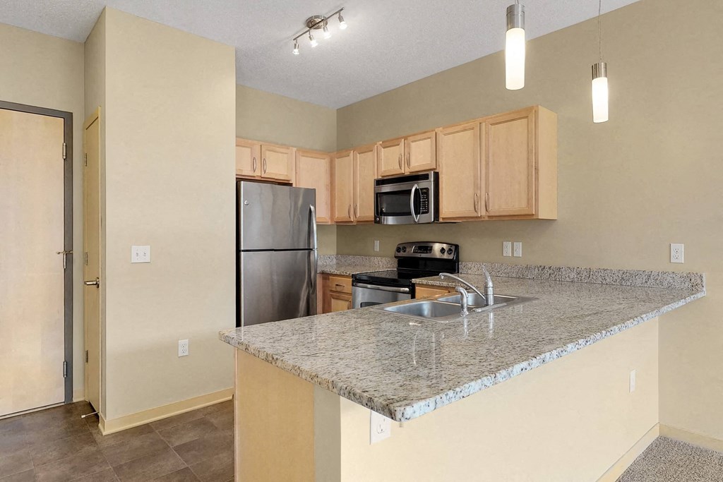 a kitchen with a granite counter top and a stainless steel refrigerator