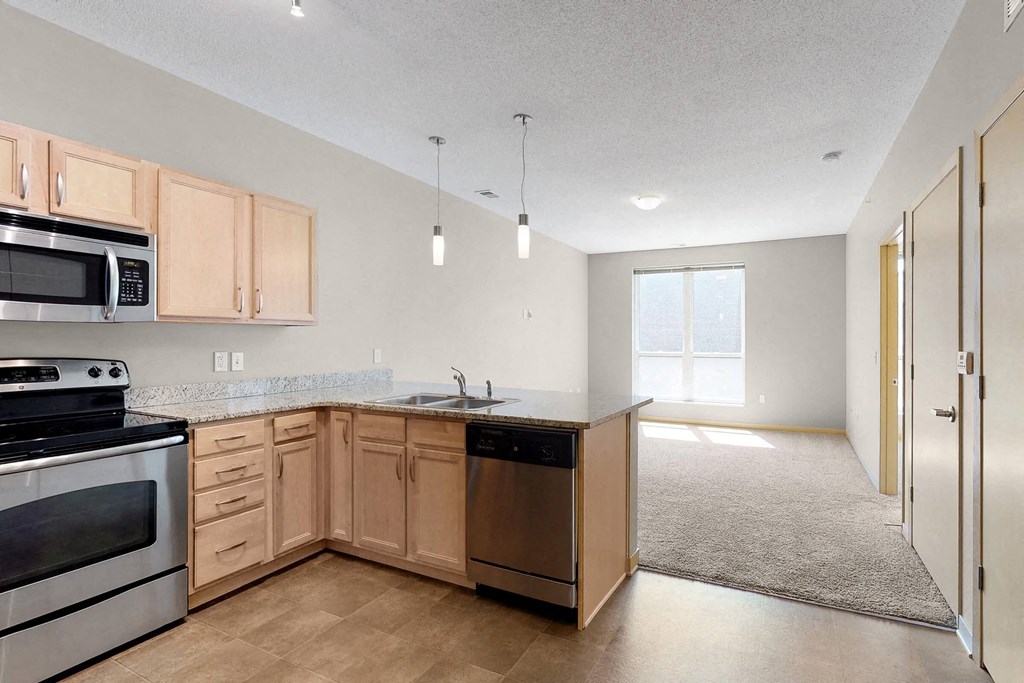 an empty kitchen with wooden cabinets and stainless steel appliances