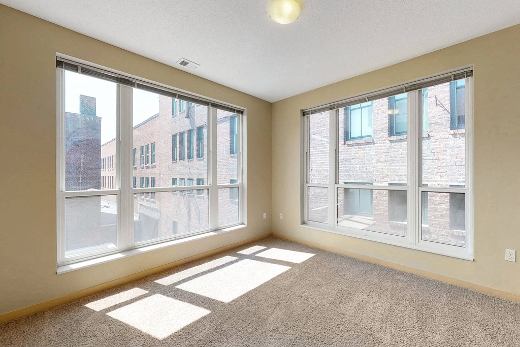 an empty living room with three large windows
