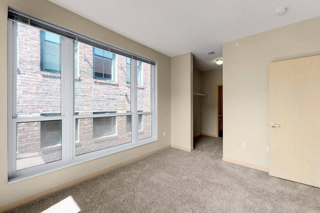 a bedroom with a large window and carpeted flooring
