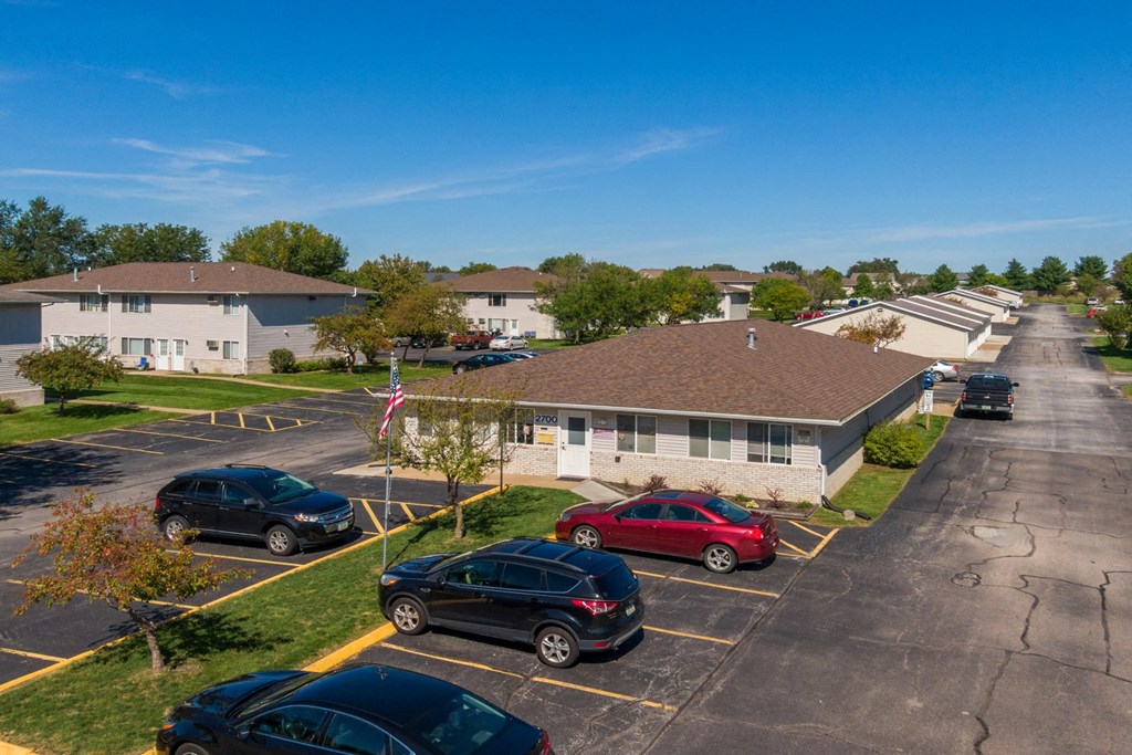 an aerial view of a parking lot with cars parked in front of buildings