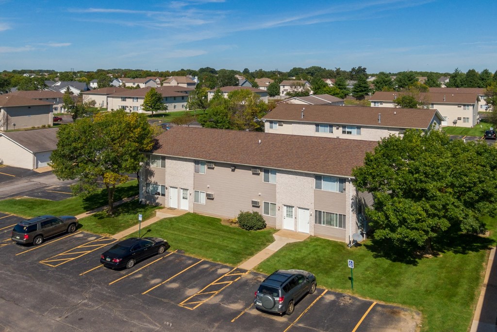 an aerial view of an apartment complex with cars parked in a parking lot