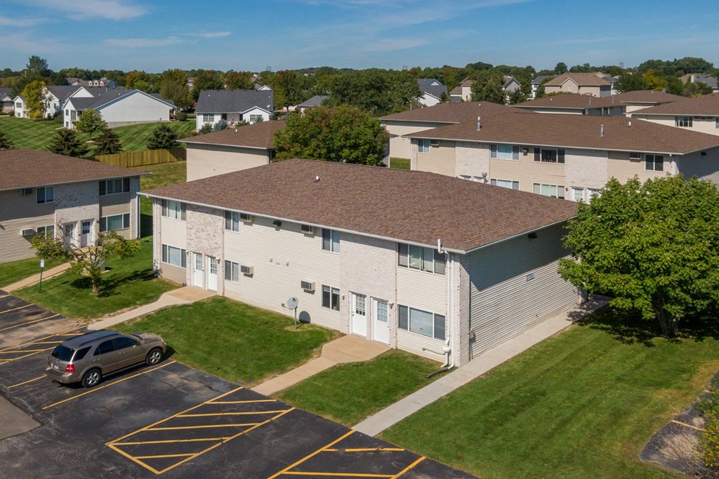 an aerial view of an apartment building with a parking lot and grass