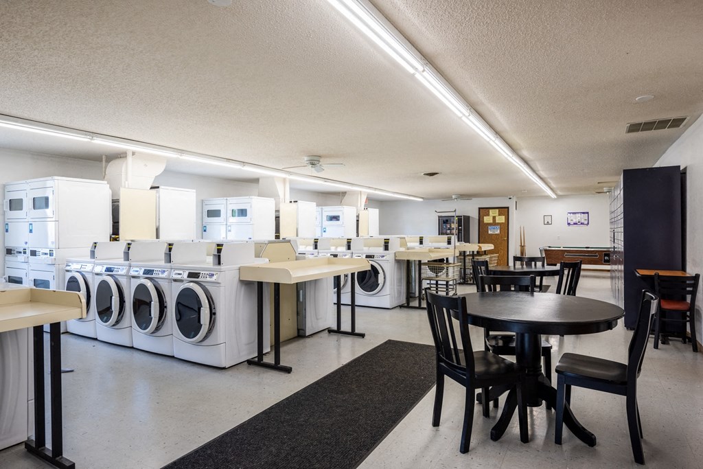 a laundry room with tables and washers and dryers and a table and chairs