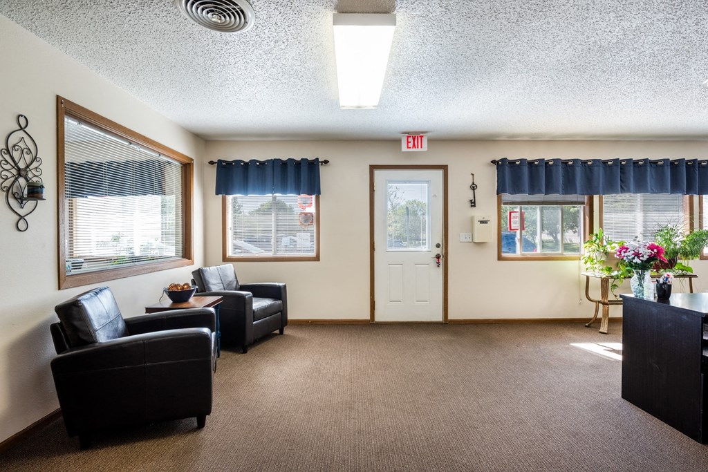 a common room with couches and chairs and a table with flowers