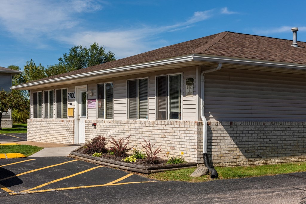 a white brick house with a porch and a parking lot