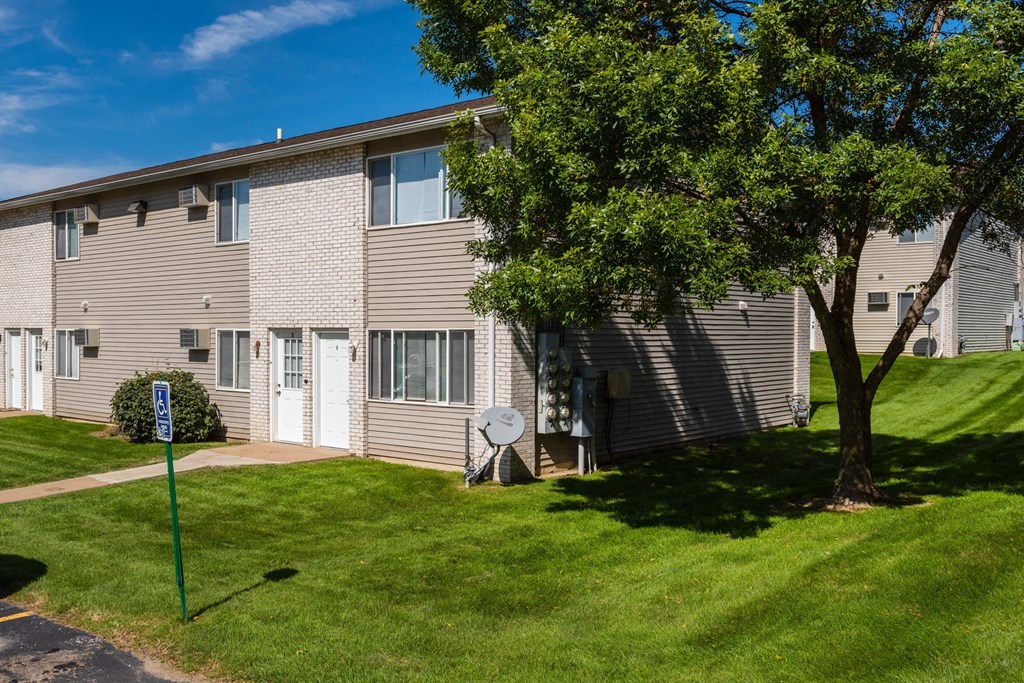 an apartment building with a yard and a tree