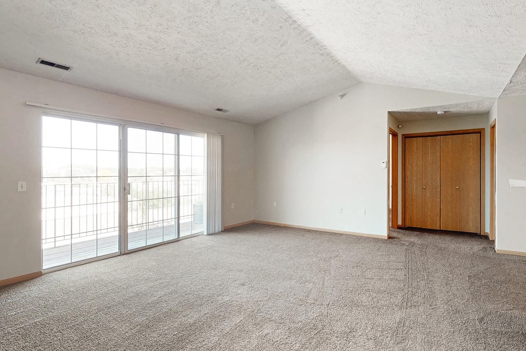 an empty living room with a door to a balcony
