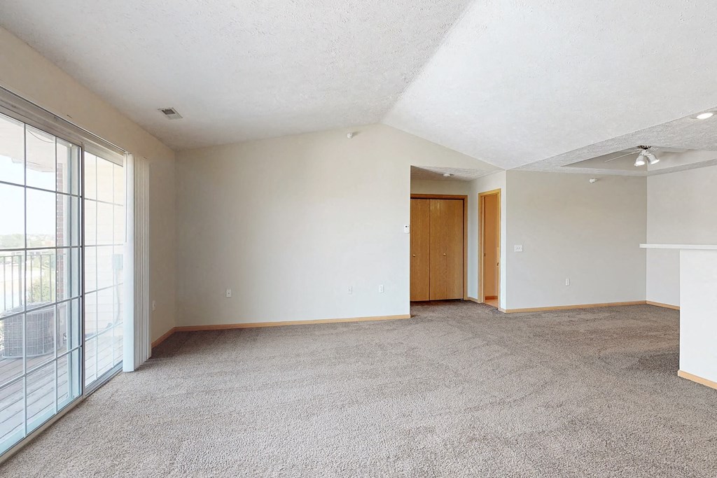 an empty living room with a large window and carpet