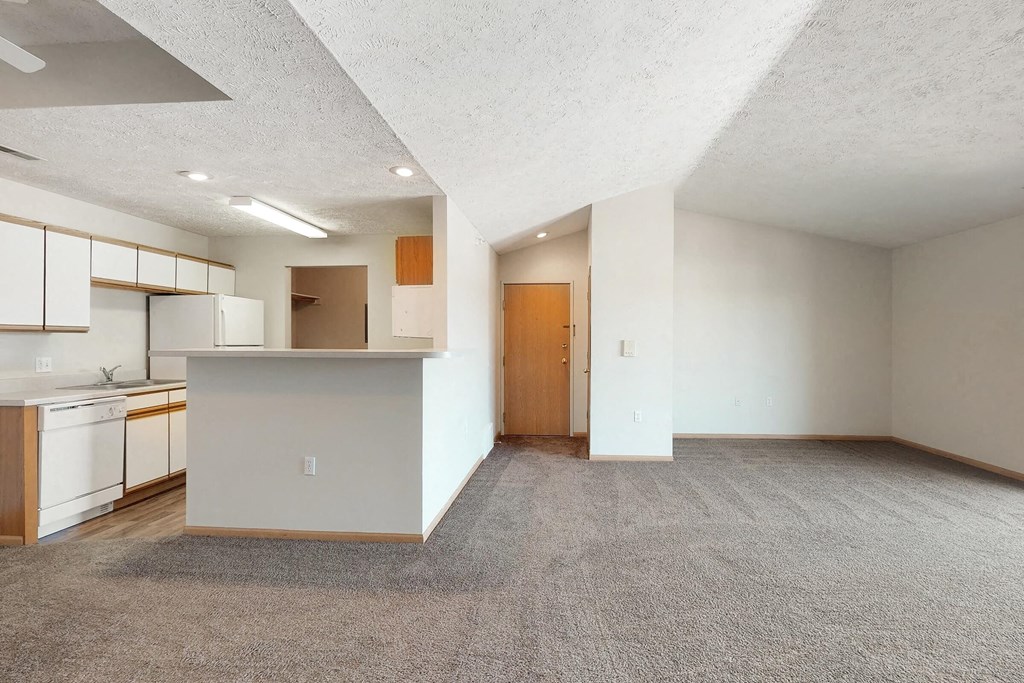 an empty living room and kitchen with white walls and flooring