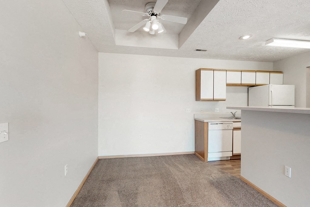 an empty living room and kitchen with a ceiling fan