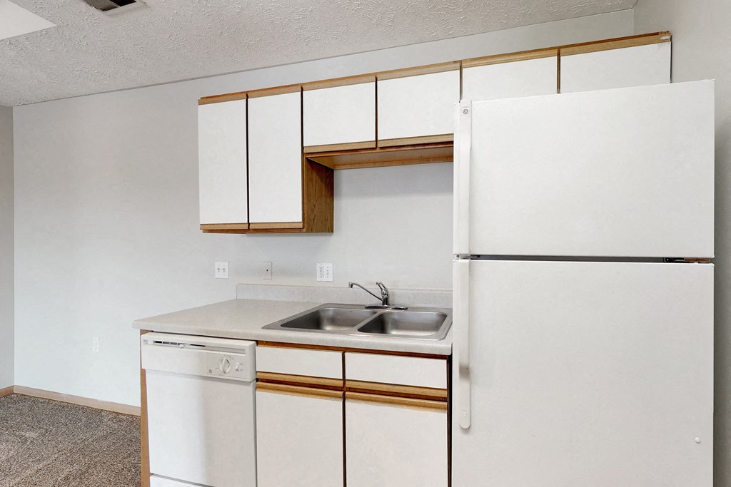 an empty kitchen with white appliances and white cabinets