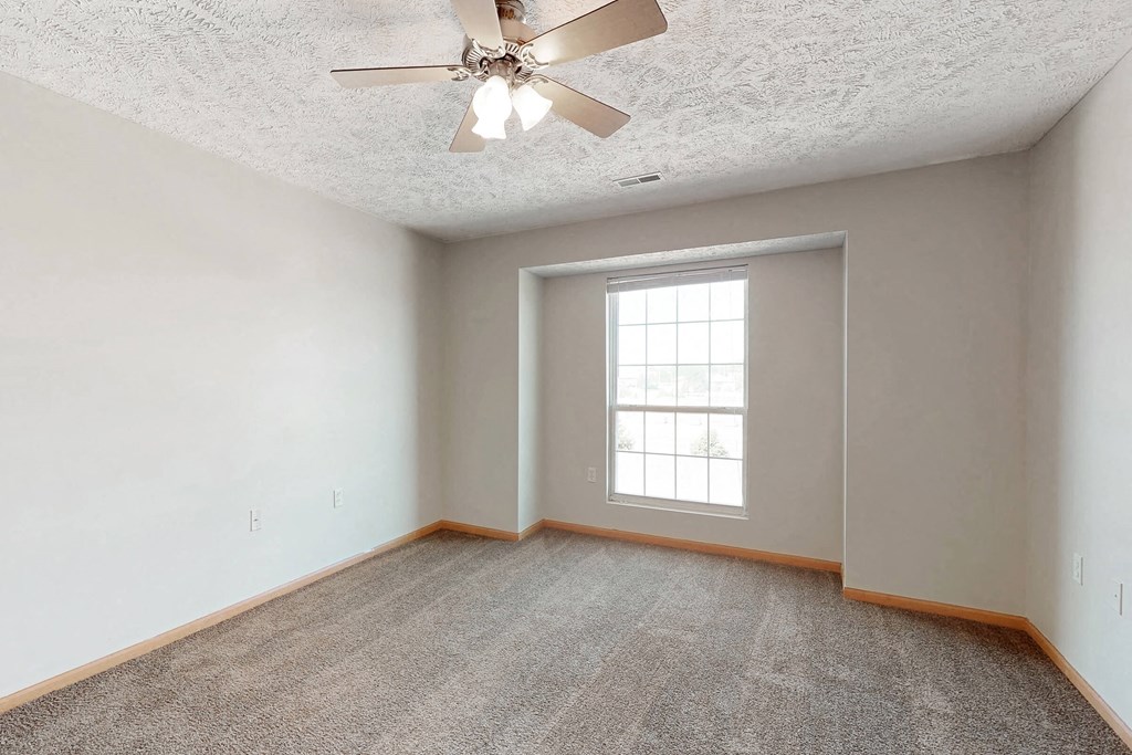 an empty living room with a ceiling fan and a window
