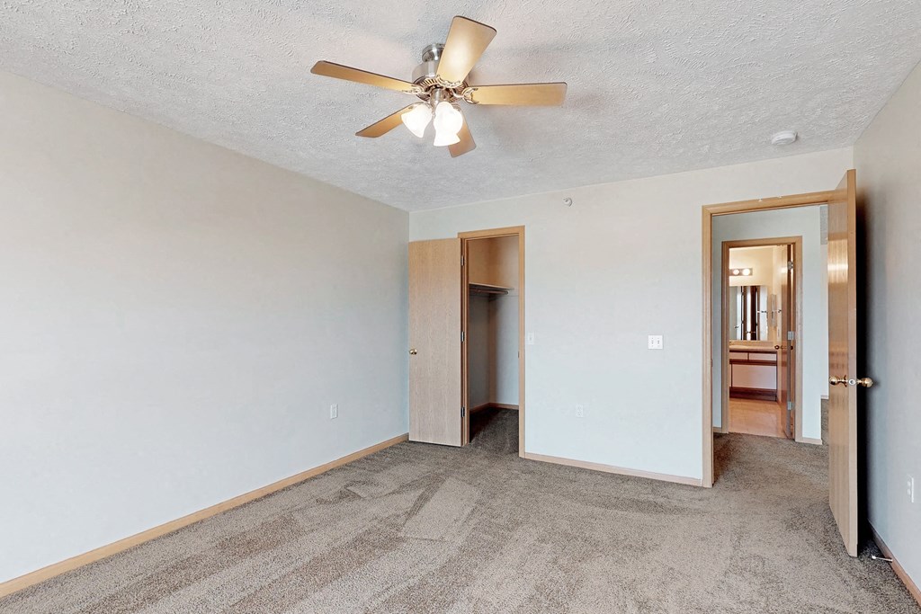 a living room with a ceiling fan and a door to a bathroom