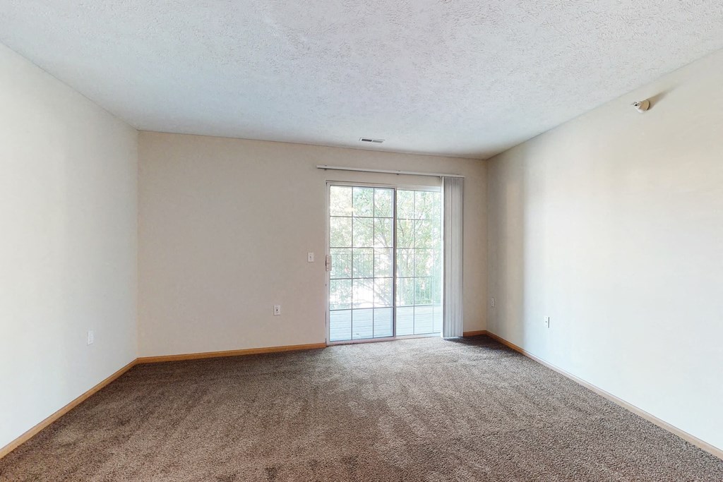 an empty living room with a door to a patio
