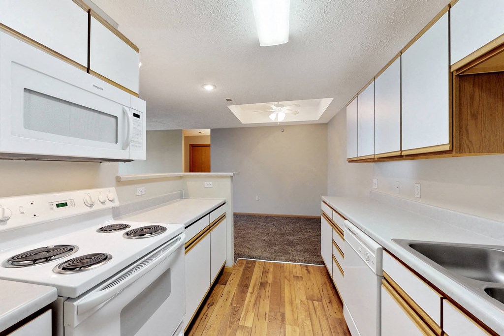an empty kitchen with white appliances and white cabinets