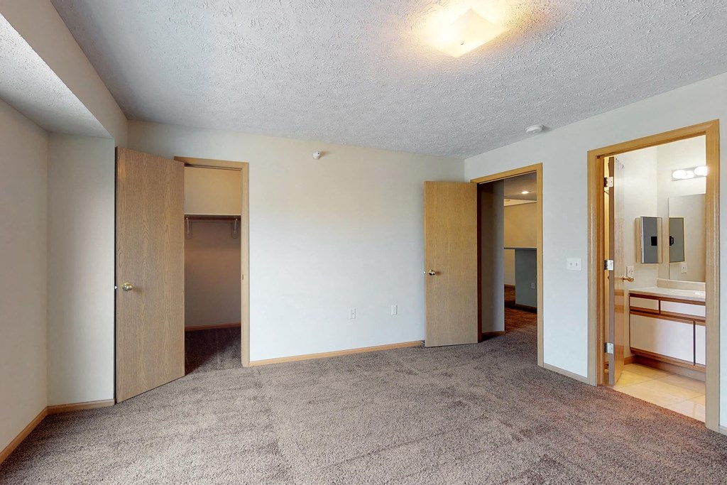a bedroom with a carpeted floor and a bathroom with mirrors