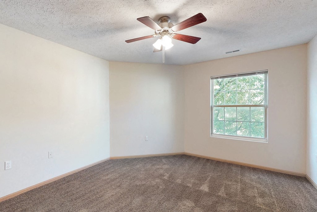 an empty living room with a ceiling fan and a window