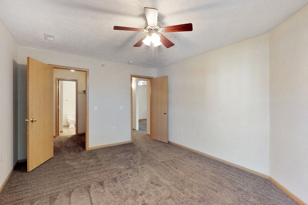 an empty room with a ceiling fan and a door to a bathroom