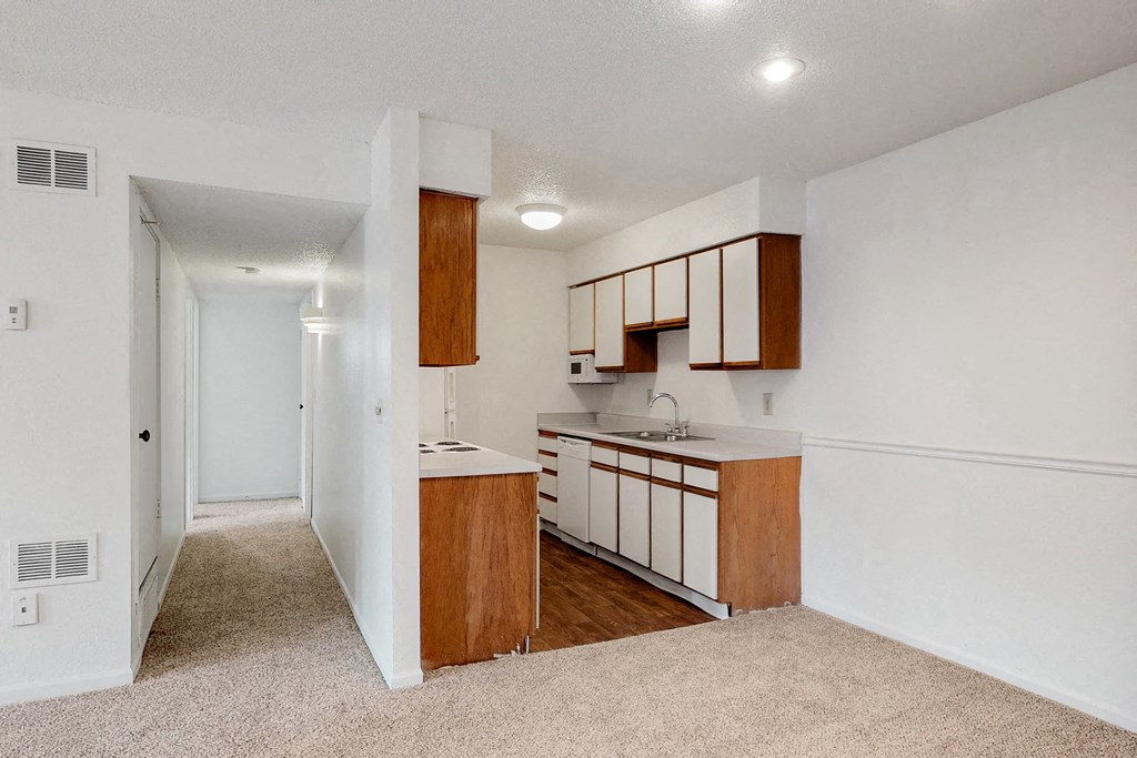 an empty kitchen with white walls and wooden cabinets