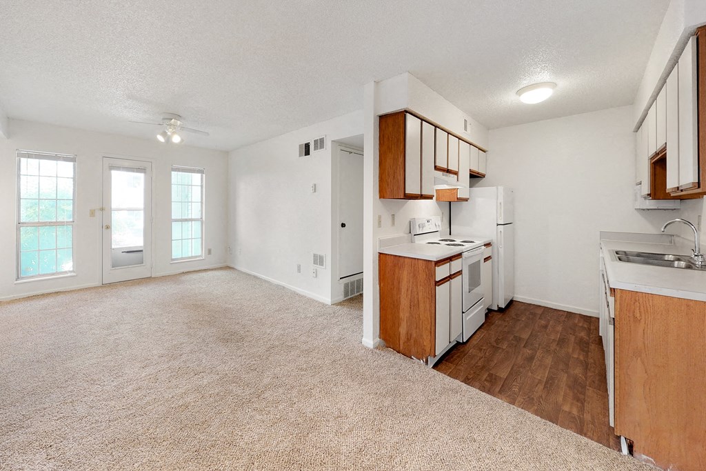 an empty kitchen with white appliances and wood floors