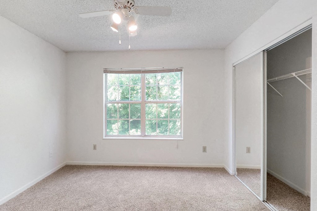 an empty bedroom with a window and a closet