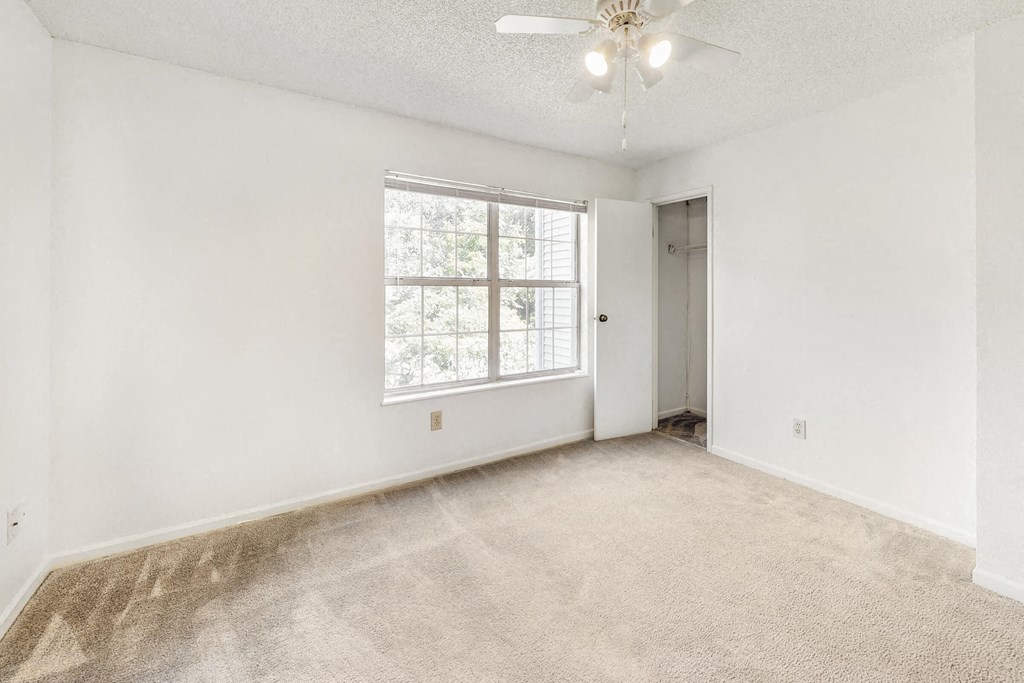 an empty living room with a large window and carpeting