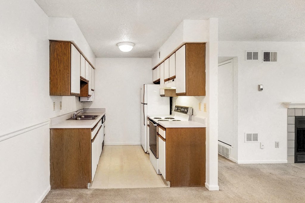 an empty kitchen with wooden cabinets and white appliances