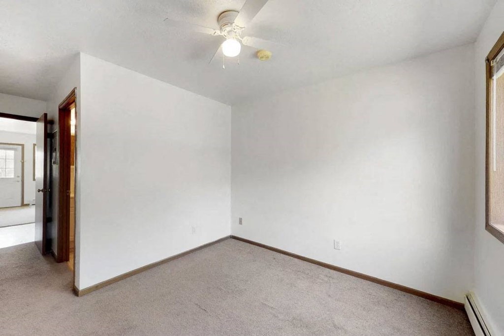 an empty living room with white walls and a ceiling fan