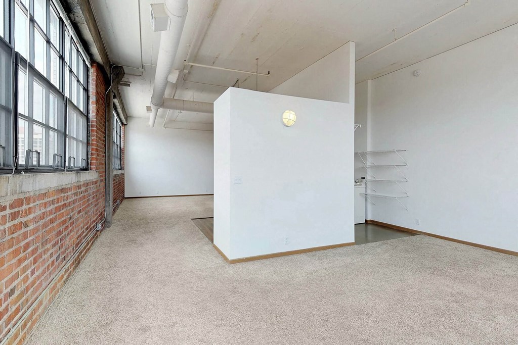 an empty room with a white wall and a brick wall