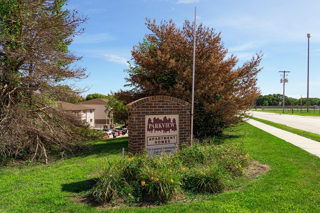 a brick sign sits in the grass next to a street