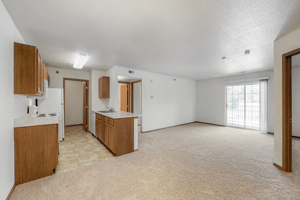 an empty living room and kitchen with white walls and wood cabinets