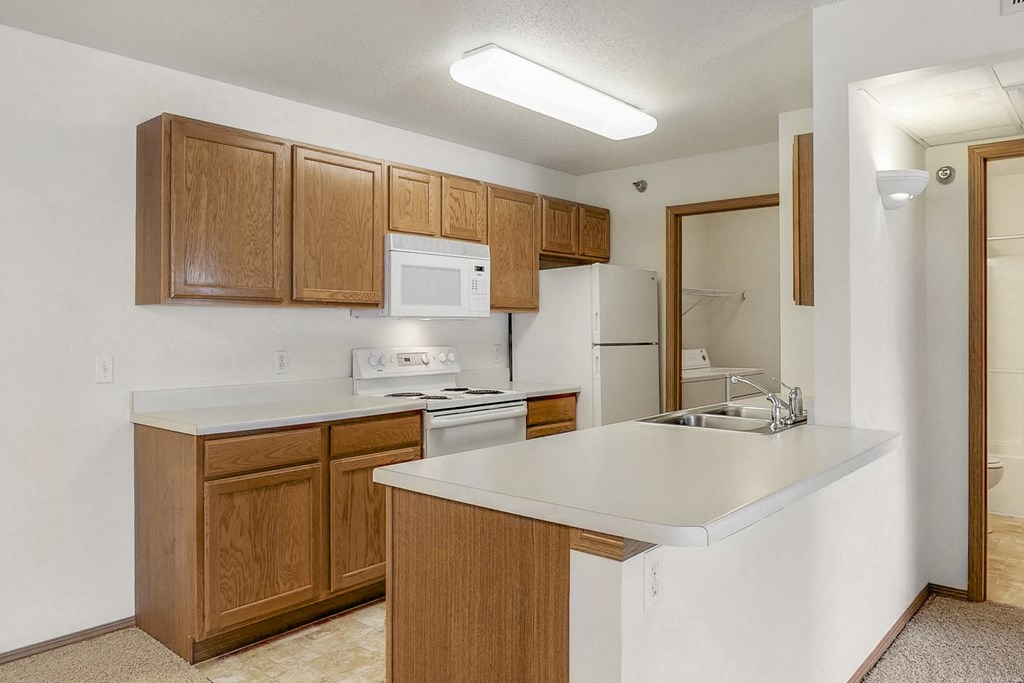 a kitchen with a white counter top and wooden cabinets