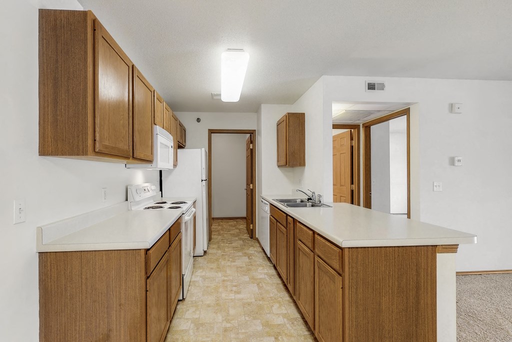 an empty kitchen with wood cabinets and white counter tops